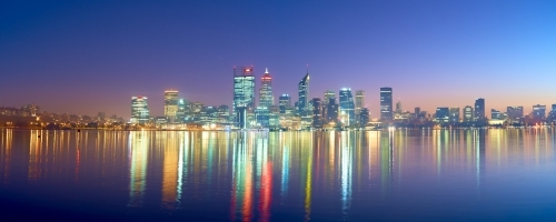 Panoramic shot of Perth skyline at dawn with colorful building lights reflected on water