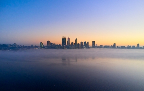 Perth skyline at dawn with fog on the Swan River surrounding the CBD - Australian Stock Image