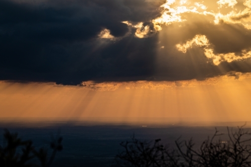Horizontal shot of rays of sunlight shining through clouds - Australian Stock Image