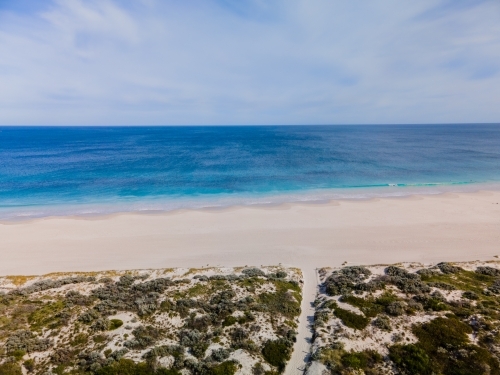 horizontal shot of Summers in Perth with white sand, green grass, ocean water and cloudy skies