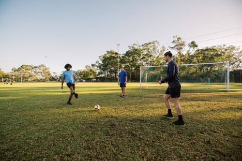 horizontal shot of three men playing soccer in the field on a sunny day with clear skies