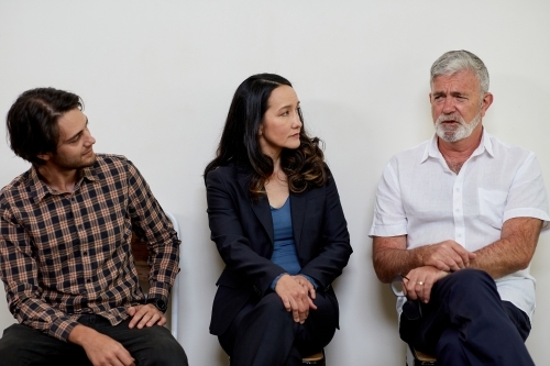 Horizontal shot of three people sitting in a row - Australian Stock Image