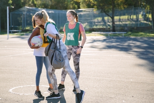 horizontal shot of three young women with two hugging each other on a sunny day with tree shadows - Australian Stock Image