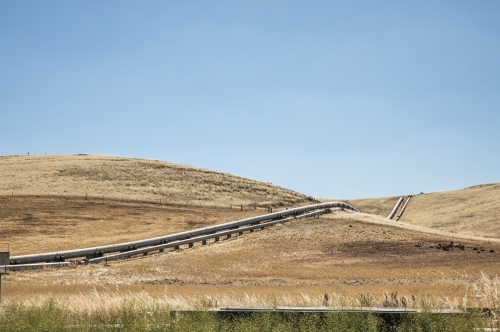 Horizontal shot of waterpipes on hill through farmland - Australian Stock Image