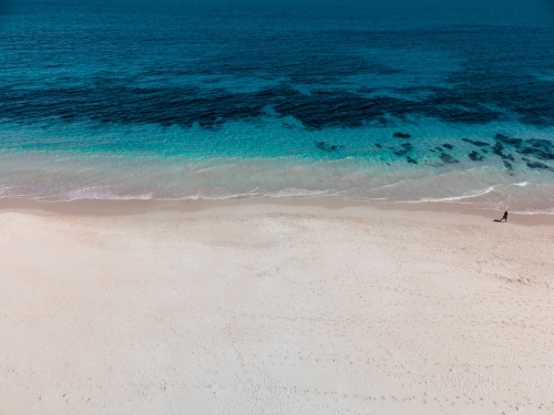 horizontal shot of white sand beach with waves and seaweeds on a sunny day - Australian Stock Image