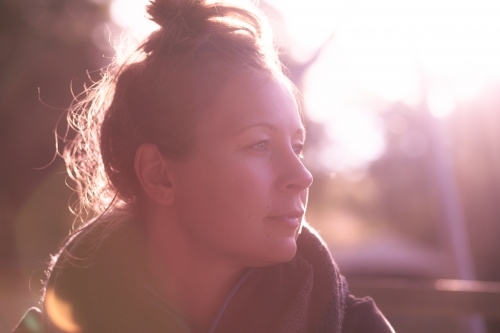 horizontal shot of woman with a messy bun hairstyle looking from a far on a sunny day - Australian Stock Image