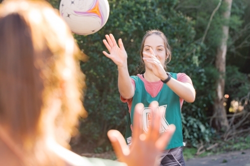 horizontal shot of young woman throwing a net ball to another woman blurred in the foreground