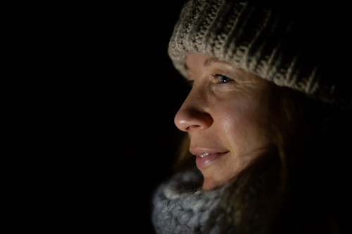 horizontal side view shot of a woman in winter clothes at night - Australian Stock Image