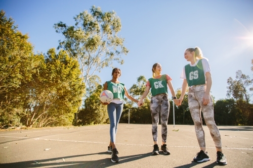 horizontal sunny outdoor shot of three young women in sports wear holding each others hands - Australian Stock Image