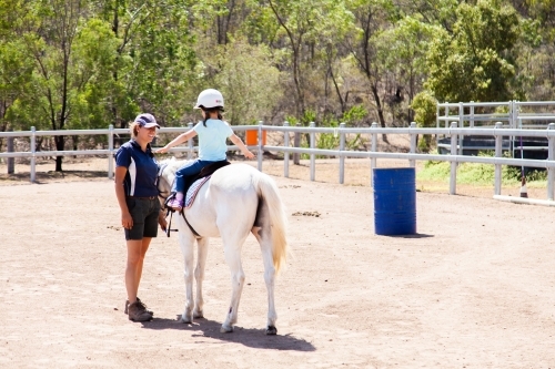 Horse riding instructor giving lesson to student on horseback - Australian Stock Image