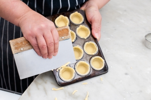 Hospitality worker cutting pastry from a tray - Australian Stock Image