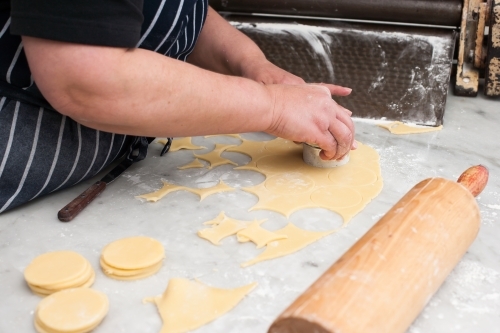 Hospitality worker cutting pastry in circles - Australian Stock Image