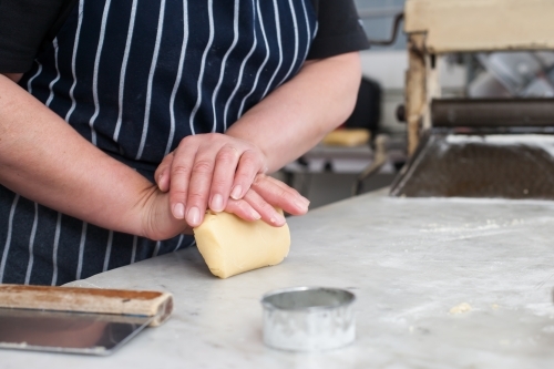 hospitality worker kneading dough in a commercial kitchen - Australian Stock Image