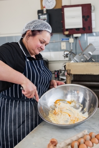 hospitality worker mixing eggs in a bowl - Australian Stock Image