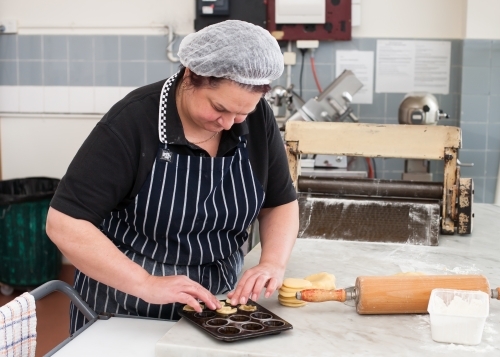 Hospitality worker working pastry into a tray - Australian Stock Image