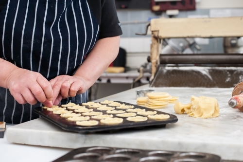 Hhospitality worker working pastry into a tray - Australian Stock Image