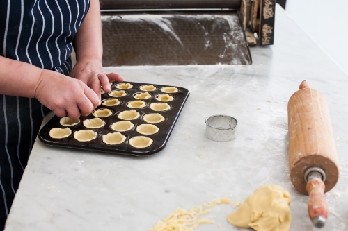 Hospitality worker working pastry into a tray - Australian Stock Image