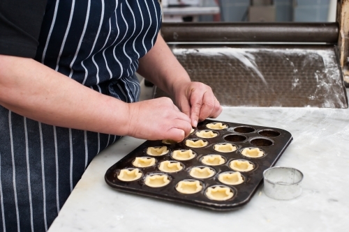 hospitality worker working pastry into a tray - Australian Stock Image
