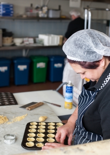hospitality worker working pastry into a tray - Australian Stock Image