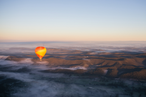 hot air balloon above the Clouds lying over hills - Australian Stock Image