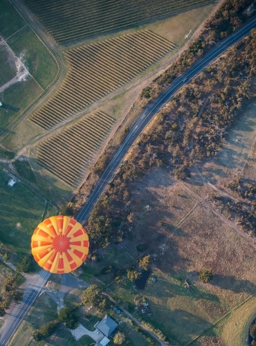Hot air balloon appears to be travelling on road.