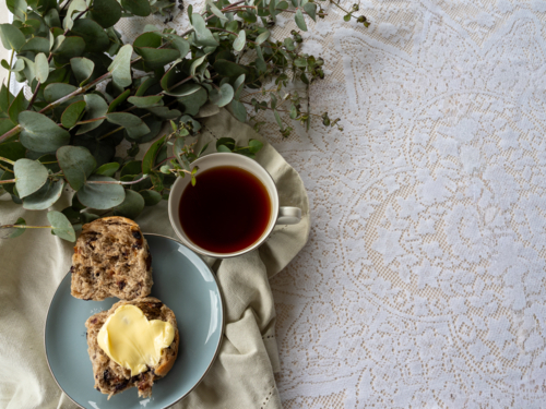 Hot Cross Bun on a plate with a cup of tea and eucalyptus branch - Australian Stock Image