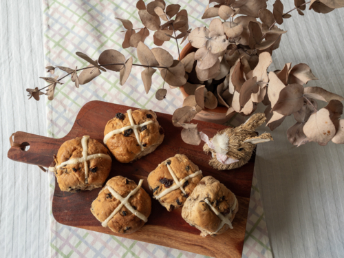 Hot cross buns on wooden serving tray with dried eucalyptus and rabbit decoration on table top - Australian Stock Image