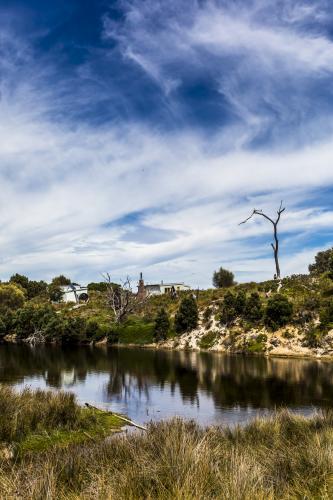 House on an island, with the dunes and trees reflected in a river. - Australian Stock Image