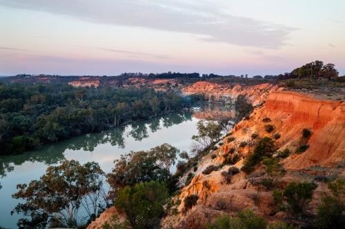 houseboat moored near bend in river at sunset