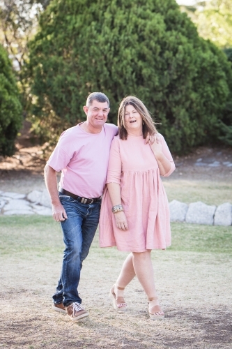Husband and wife couple in 50s walking together laughing - Australian Stock Image