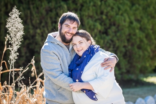 Husband and wife outside in garden cuddling close together - Australian Stock Image
