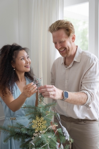 Husband and wife placing star on Christmas tree together