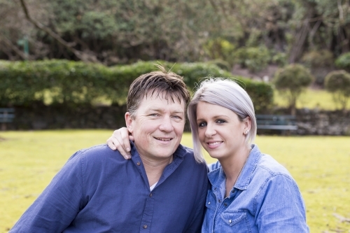 Husband and wife sitting closely with one arm on the other - Australian Stock Image