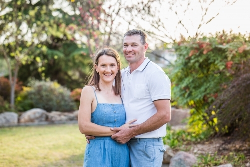 Husband and wife standing together in garden touching - Australian Stock Image