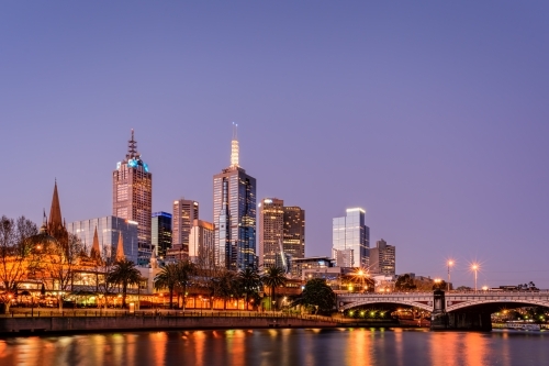 Illuminated Melbourne City skyline by Princes Bridge Over Yarra River Against Clear Sky