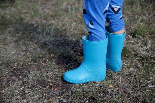 Image of a child's legs wearing light blue gumboots - Australian Stock Image
