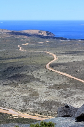 View along dirt road towards ocean from top of hill - Australian Stock Image