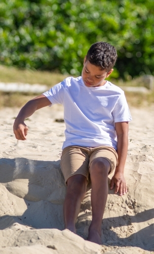 Indigenous boy playing on a sand ledge