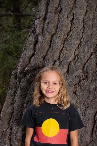 Indigenous girl near old bark tree trunk - Australian Stock Image