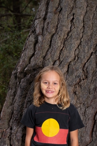 Indigenous girl near old bark tree trunk