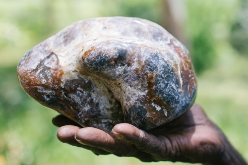 Indigenous hand holding stone - Australian Stock Image