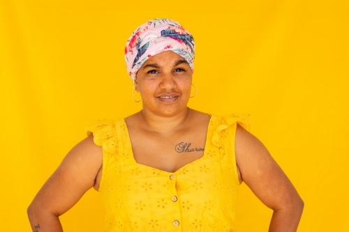 Indigenous Nyoongar woman wearing yellow against yellow backdrop - Australian Stock Image