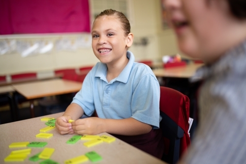 Indigenous primary school student smiling working with coloured word tiles