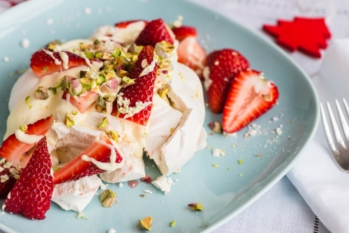 Individual dessert for christmas, a smashed meringue topped with cream, strawberries, pistachio - Australian Stock Image