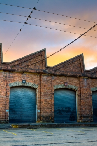 Industrial rail shed with warehouse roller doors during sunrise