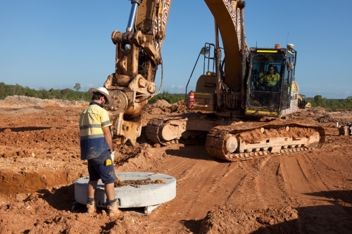 Industrial worker overseeing heavy machinery on a building site - Australian Stock Image