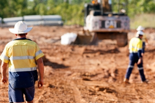 Industrial workers on a building site with heavy machinery in the background - Australian Stock Image