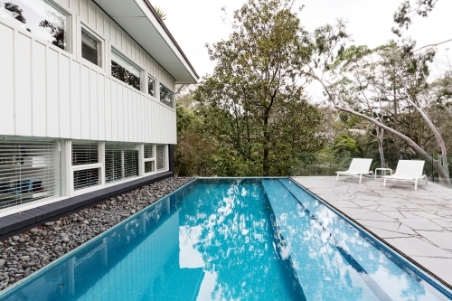 Infinity edge pool in backyard of mid century Australian luxury home - Australian Stock Image