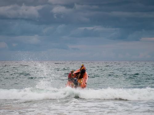 Inflatable dinghy heading out to sea through the waves - Australian Stock Image