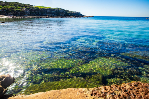 interesting rock formations visible from the clear waters of Little Bay beach - Australian Stock Image